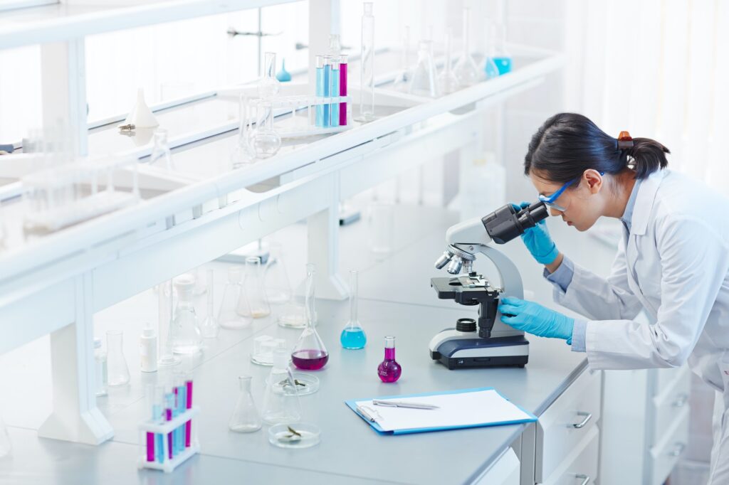 Researcher using a light microscope in medical cleanroom