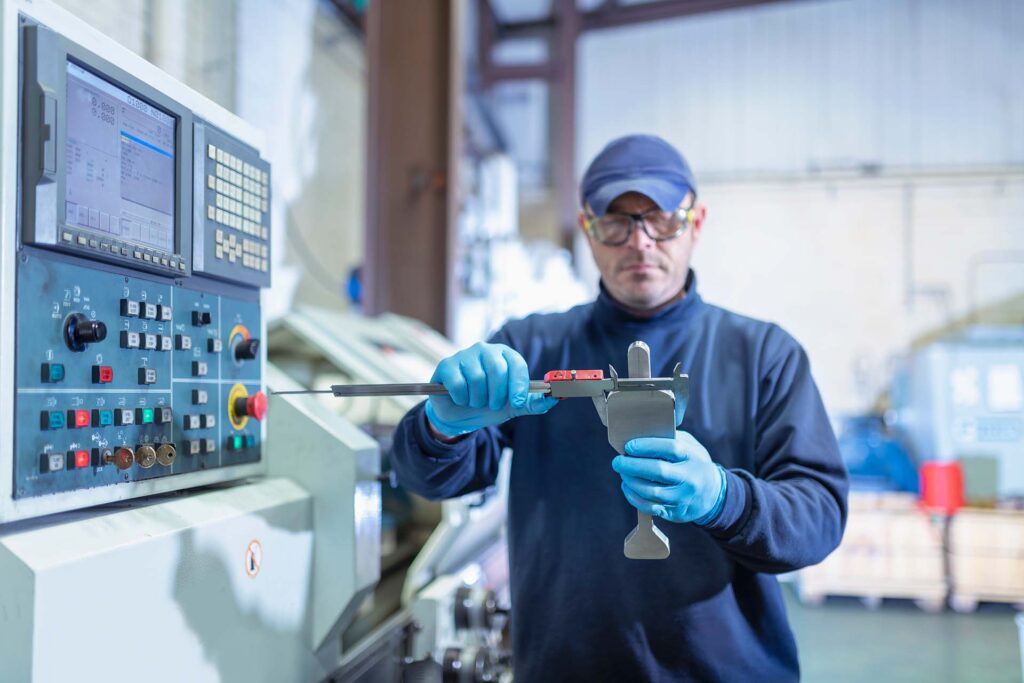 Engineer measuring metal part using a caliper
